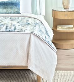 a bed with a white bedspread on top of it next to a night stand