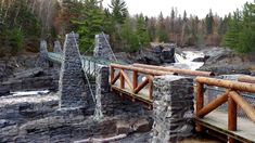 a wooden bridge over a river surrounded by forest