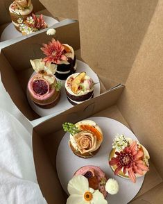 three boxes with different types of cupcakes in them and flowers on the top