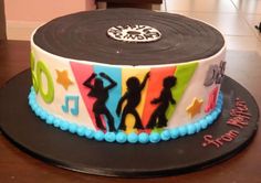 a birthday cake decorated with the silhouettes of people dancing on it's side