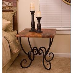 two candles sitting on top of a wooden table next to a bed in a bedroom