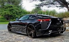 a black sports car parked in front of some trees