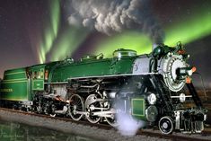 an old fashioned steam train with the northern lights in the background