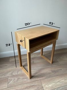 a small wooden desk with measurements for the top and bottom drawers on each side, in front of a white wall