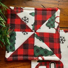 two red and black plaid christmas coasters on a wooden table