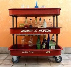 an old radio flyer bar cart with liquor bottles on it