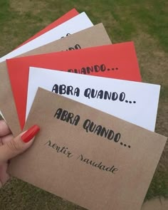 a person holding four envelopes with writing on them in front of some grass and trees