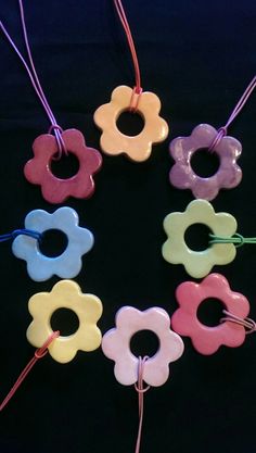 several different colored flower shaped beads are arranged in a circle on a black background with red string