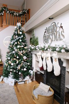 a decorated christmas tree in front of a fireplace with stockings hanging from the mantel