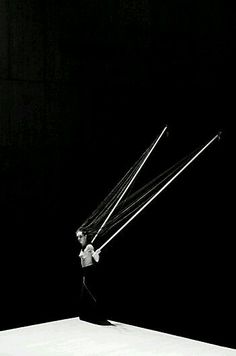 a man holding two strings in his hands while standing on top of a white surface