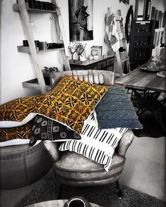 a black and white photo of a living room with pillows on the couch, chairs in the background