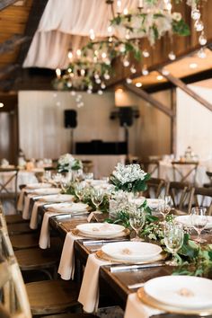 the tables are set with white plates and silverware for an elegant wedding reception in a barn