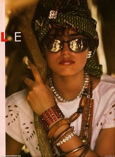 a woman wearing sunglasses and jewelry on the cover of people magazine, with her hand resting on a tree branch