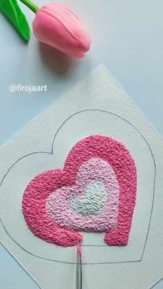 a pink heart on top of a piece of paper next to a tulip flower