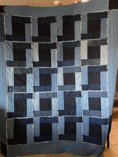 a blue and black quilt hanging on a wall next to a tiled floor in a room