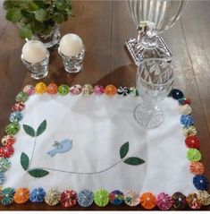 a table topped with a glass vase filled with flowers next to a white place mat