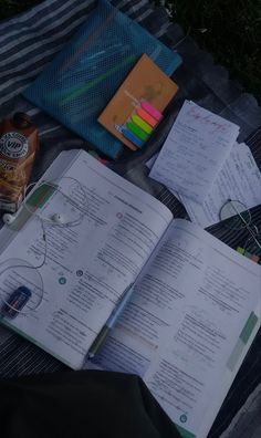 an open book sitting on top of a blanket next to a bottle of alcohol and other items