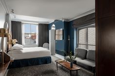 a hotel room with blue walls and grey carpeted flooring, a bed in the middle