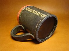 a cup that is sitting on top of a table with a leather strap around it