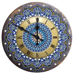 a decorative clock with blue and gold designs on it's face, against a white background