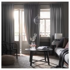 a living room filled with furniture and a window covered in grey drapes next to a couch