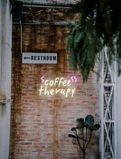 a brick wall with a neon sign that says coffee therapy