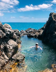 a man swimming in the ocean near some rocks