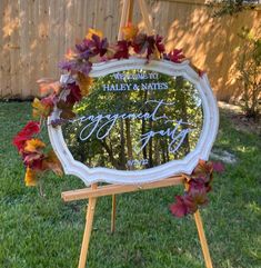 a mirror that is on top of a easel in the grass with leaves around it