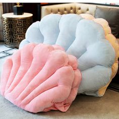 a large pink and blue pillow sitting on top of a floor next to a chair