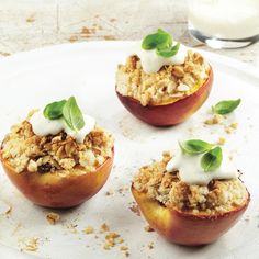 three baked apples topped with crumbled toppings on a white plate next to a glass of milk