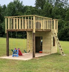 a wooden play house with a swing set and slide