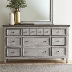 a dresser with a mirror and vase on top