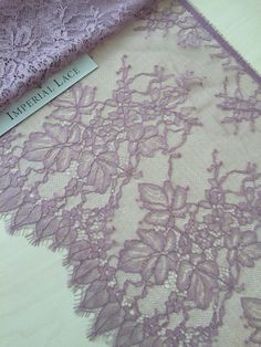 two pieces of purple lace sitting on top of a wooden table next to each other