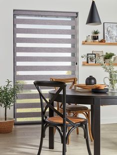 a dining room table with chairs and a window covered in vertical blind shades on the windowsill