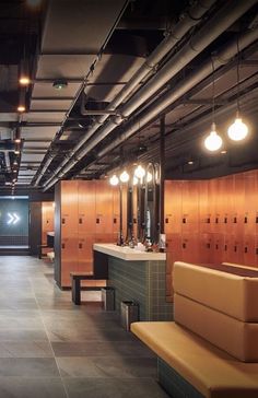 a public restroom with benches and lights on the ceiling is pictured in this image, it appears to be empty