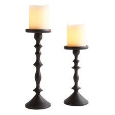 two candles sitting on top of each other in front of a white background and one is lit