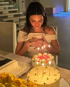 a woman sitting in front of a cake with lit candles