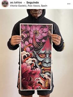 a man in a hoodie holding up a poster with an image of a demon on it