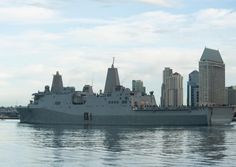 a large battleship floating on top of a body of water next to tall buildings in the background