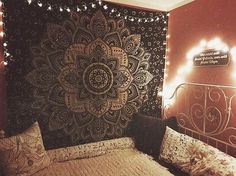 a bed with pillows and lights on the headboard is in front of a tapestry