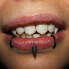 a close up of a person's mouth with piercings on the end of it