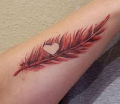 a feather with a heart tattoo on the arm