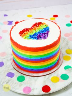 a rainbow cake on a plate with confetti