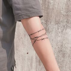 a person with a barbed wire tattoo on their arm and wrist is standing next to a concrete wall