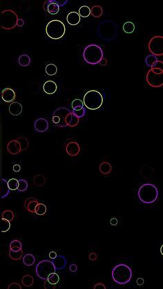 colorful circles are flying in the air on a black background with white and red lights