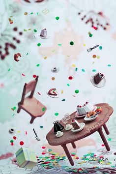 a table with plates and cups on it in front of confetti falling from the ceiling