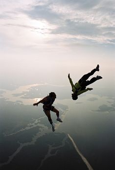 two people are flying in the air with their feet up and one is upside down