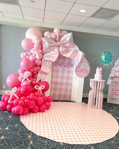 a pink and white baby shower themed party with balloons on the floor, checkered table cloth