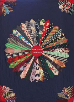 a quilted wall hanging with many different colored ties on it's center piece