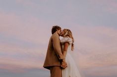 a bride and groom kissing in front of the sunset at their beach wedding venue,